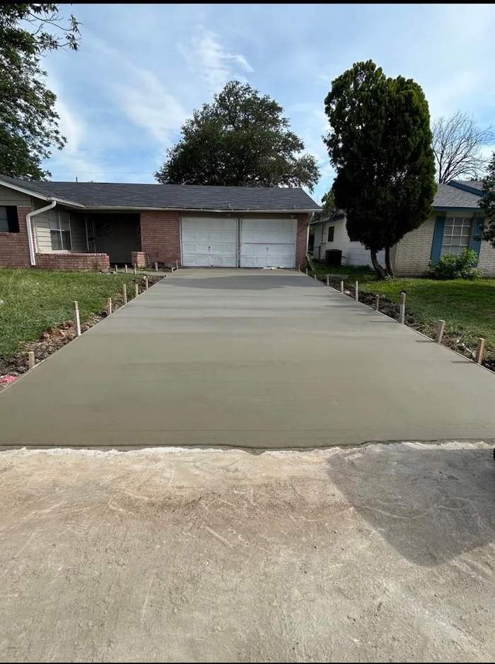 New concrete driveway running up to a two car garage with forms still set